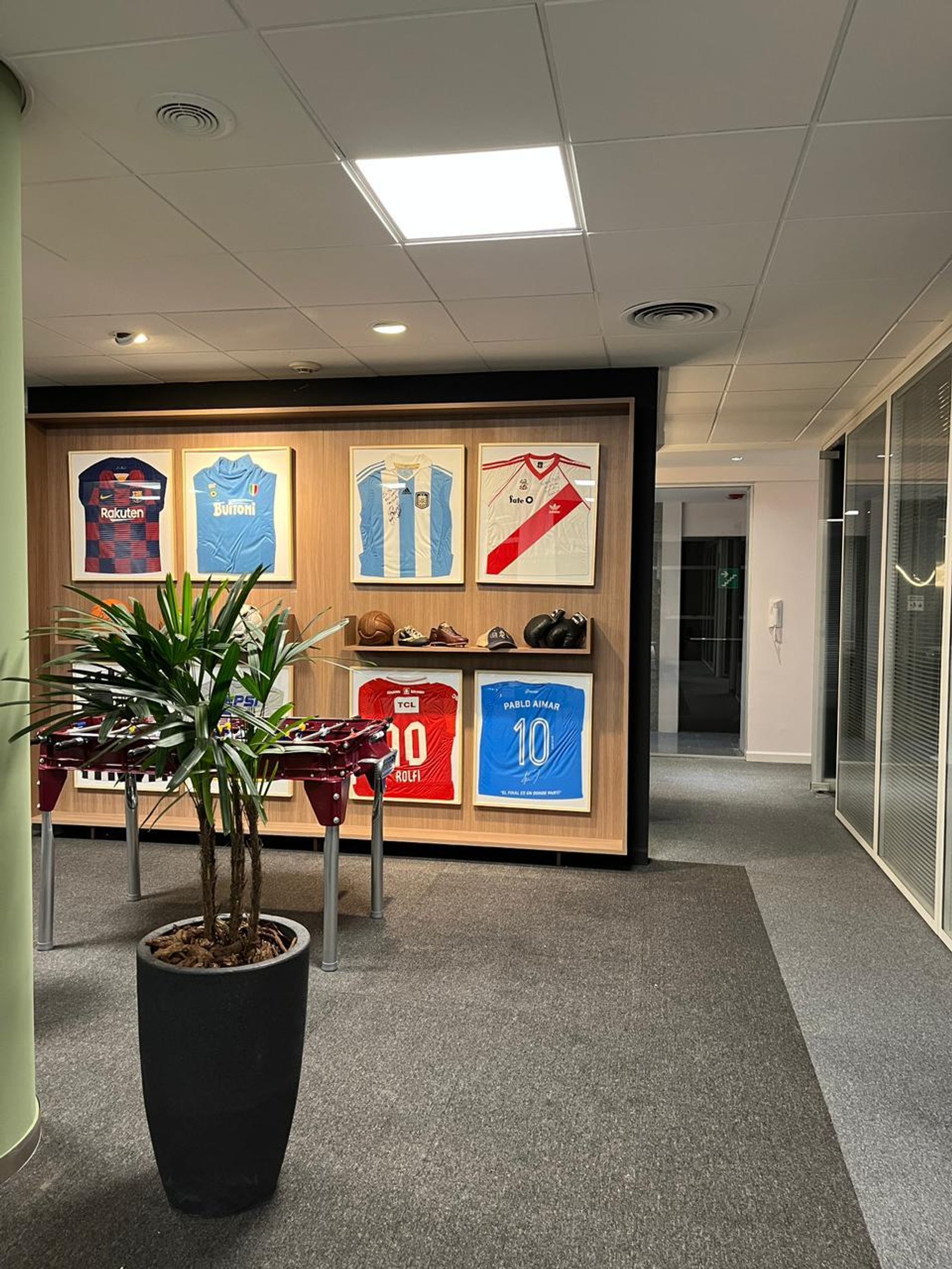 Oficina moderna con camisetas de fútbol y planta grande — proyecto Oficinas Cordoba, por Arcucci Arquitectura, en Av. Córdoba